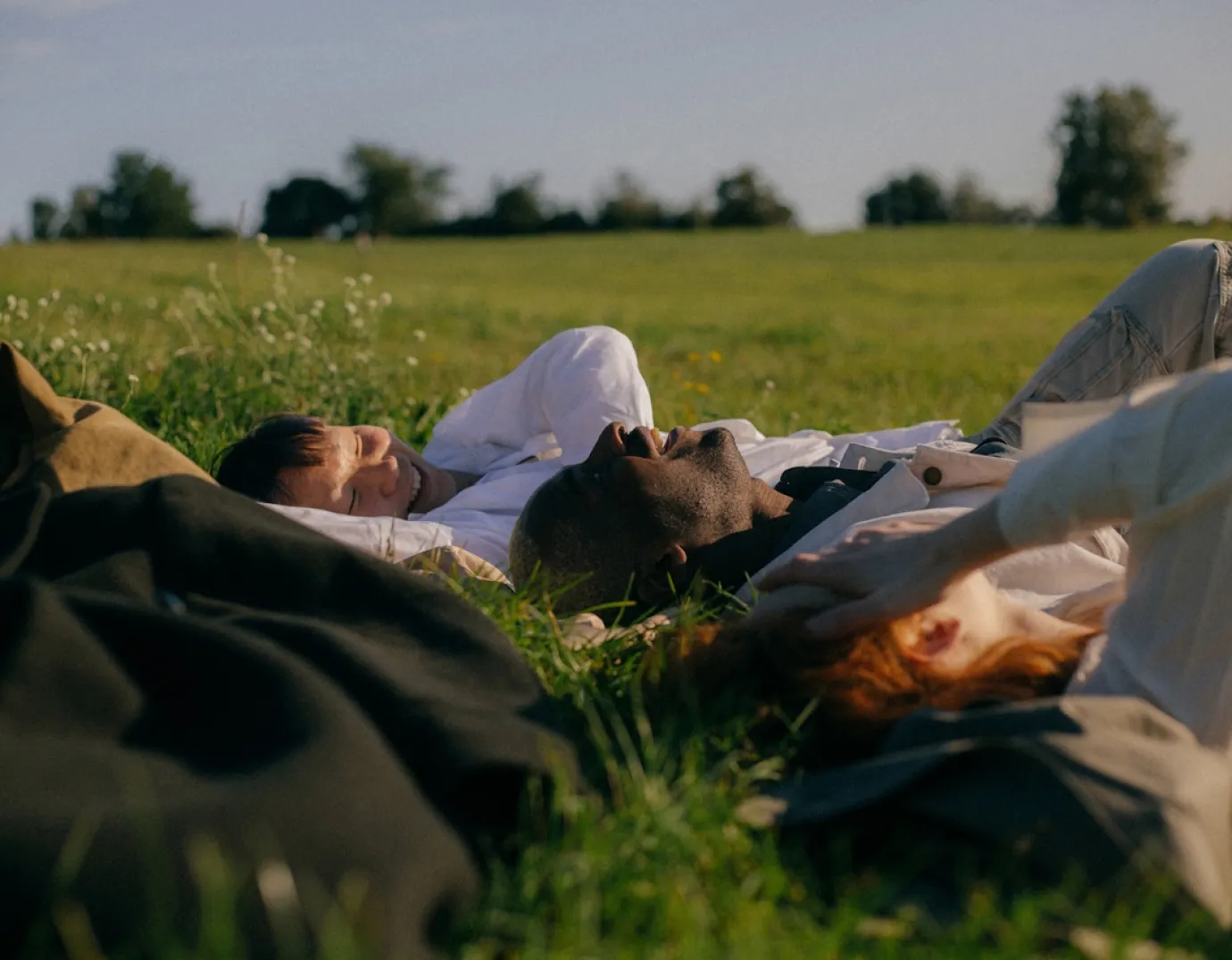 Two people lying in a meadow during a guided wellness retreat focused on rest, meditation, and nervous system recovery.