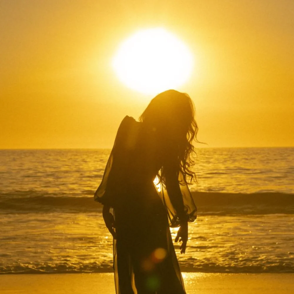 Woman standing in golden light on the beach, embodying inner radiance and alignment, yacht charter holidays